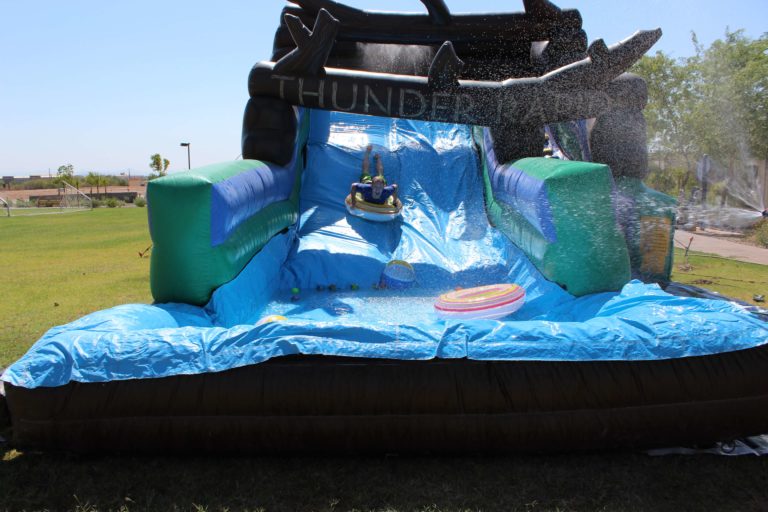 young boy rides tube down inflatable water slide